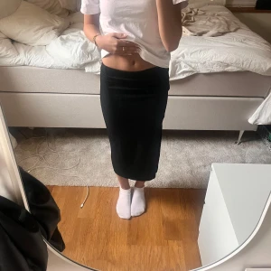 Svart ribbad lång kjol  - Svart ribbad kjol med slits på sidan. Har en tight passform