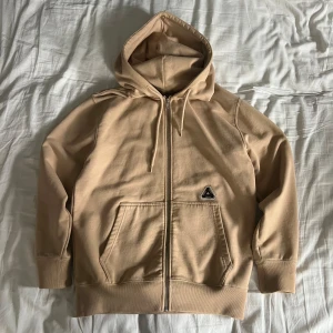 Beige zip up från Palace Skateboards - Säljer en beige hoodie från Palace Skateboards. Köpt för länge sedan i Palace butiken i London. S i storleken men sitter relativt stort