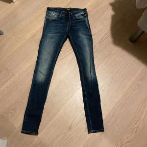 Blå jeans från Replay - Snygga blå jeans från Replay med en tight passform. De har en klassisk femficksdesign och en lätt tvättad look som ger en cool stil. Perfekta för en avslappnad vardagslook.