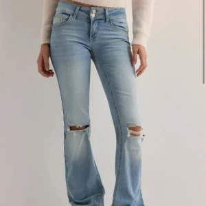 Ljusa bootcut jeans med slitningar - Snygga ljusblå bootcut jeans med slitningar på knäna. De har en låg midja och klassisk femficksdesign med knappar fram. Perfekta för en avslappnad stil. Nypris 700kr🩷🩷