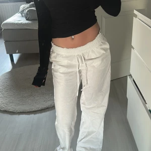 Vita linnebyxor med snörning - Säljer ett par vita linnebyxor med elastisk midja och snörning. Byxorna har en loose passform och är perfekta för en avslappnad stil. De är tillverkade i ett lätt och luftigt material som passar bra för varmare väder.