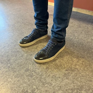 Lanvin - Snygga blå sneakers med svarta, blanka tåkappor och snörning. Skorna har en vit sula som ger en fräsch kontrast. Perfekta för en stilren look. Skick 9/10. Ända defekten är insida häl men syns ej när de sitter på. Kom med fler bilder eller minsta lilla fråga. Storlek Uk 8 vilket motsvara ungefär 43.