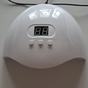 Vit LED-lampa för naglar - Säljer en vit LED-lampa för naglar med digital display och tre knappar för tidsinställning. Den har en USB-anslutning för enkel användning. Perfekt för hemmabruk för att härda gelnaglar snabbt och effektivt.