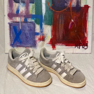  Adidas Campus  - Snygga grå Adidas Campus sneakers i mocka med vita detaljer och snörning. Perfekta för en stilren look med klassiska tre ränder på sidan och Adidas-logga på plösen. Dem är i ett väldigt bra skick och använda ca 10 gånger, skick 7,5/10. Om du undra något är det bara att skriva, svar så snabbt jag kan😁🙌