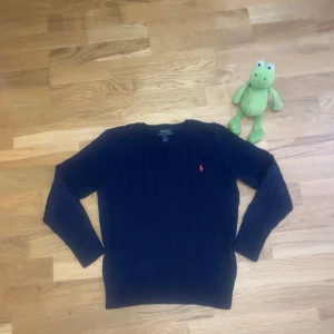 mörkblå ralph lauren cable knit 🧶  - Ralph Lauren kabelstickad tröja i 100% bomull 🌟    Nästan aldrig använd, i perfekt skick utan defekter 🧵    En klassisk bit som erbjuder både stil och komfort 😍    Idealisk för att lager-på-lager eller att bära ensam 👌    Perfekt för att lägga till en touch av sofistikering till vilken outfit som helst ✨    Missa inte denna fantastiska fynd! 🛍️    Storlek: Barn M👦🏻