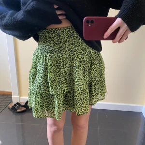 Volang kjol - Snygg grön kortkjol med leopardmönster och volangdetaljer.