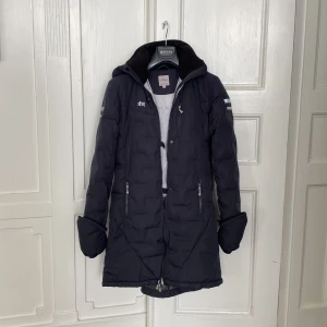 Mörkblå rid jacka från Uhip, stl 160 - Säljer en mörkblå ridjacka från Uhip med lång passform och dragkedja. I väldigt bra skick och perfekt för kalla stall och riddagar.