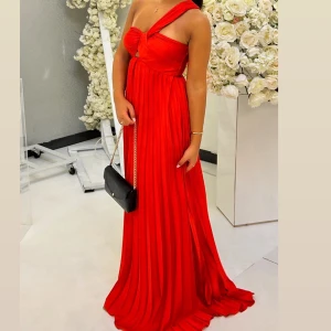 Röd oneshoulder långklänning - Snygg röd långklänning med oneshoulder-design och elegant drapering. Perfekt för en festlig kväll.  Klänningen har en unik axelbandslös stil som ger en modern touch.