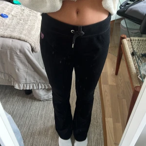 Svarta mjukisbyxor från Juicy Couture - Säljer ett par svarta mjukisbyxor från Juicy Couture med paljet-diamant detalj på baksidan. Byxorna har en bekväm passform med dragsko i midjan och är perfekta för en avslappnad stil. Pris kan diskuteras 