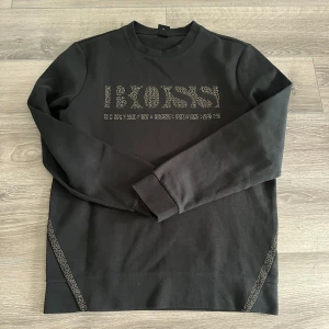 Svart tröja från Boss - En svart guld Hugo boss tröja i helt nytt skick. Inte en skavank så långt ögat kan se. Varken hål, slitage eller blekt. Nypris 1500kr. Passar både s och m. 