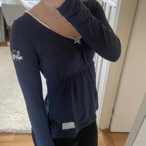 Mörkblå långärmad topp med rosett - Säljer en supersöt marinblå långärmad tröja från Odd Molly! Den är i strl 0 vilket motsvarar en XS, i mycket fint skick förutom ett pyttelitet hål som knappt är märkbart (se bild 4)🩷