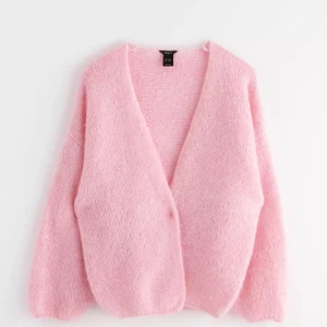 Rosa stickad kofta - Mysig rosa stickad kofta med en avslappnad passform. Perfekt för att hålla sig varm under kyliga dagar. Koftan har långa ärmar och en öppen design utan knappar.