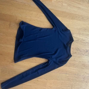 Mörkblå långärmad tunn tröja - En basic mörkblå långärmad tröja i tunn och lätt genomskinlig bomullsmix. Enkel design med rund halsringning och smal passform, perfekt att ha som lager under andra plagg eller till jeans.