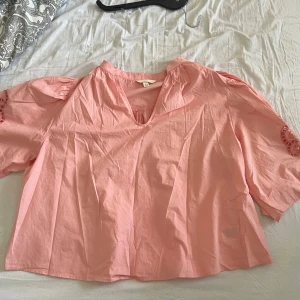 Ljusrosa blus med broderade detaljer - Supersöt ljusrosa blus från H&M med v-ringning och vida trekvartsärmar. Säljer denna blus just för att den inte kommer till användning, endast använd 2 gånger 