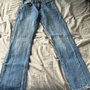  blå jeans W28 L32 - Klassiska  jeans i ljusblå denim med raka ben och normal passform. Snygg vintagekänsla med fem fickor och orange sömmar. Perfekta för dig som gillar tidlös stil och vill ha ett par riktigt schyssta jeans i garderoben.