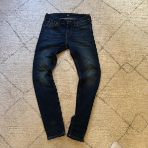 Mörkblå jeans från Lee W27 L30 - Snygga mörkblå slimfit jeans från Lee i modellen Malone. Jeansen har klassisk stil och är mer åt det slim fit hållet. Sköna fickor och knappt använda. Nypris cirka 800kr, hör av er vid frågor eller funderingar! 