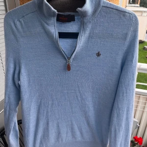 Ljusblå merinoullströja Morris S - Snygg ljusblå stickad tröja från Morris i 100% merinoull. Tröjan har half zip med läderdetalj, hög krage och broderad logga på bröstet. Perfekt för dig som gillar stilrena och bekväma plagg med premiumkänsla. Tröjan är nästan helt ny och knappt använd, säljer för den e för liten. skriv vid frågor eller funderingar!