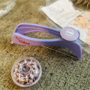 Lila ögonbrynstrådare från Sildne - Säljer en lila ögonbrynstrådare från Sildne, perfekt för att forma brynen och ta bort små hårstrån med precision. Verktyget är gjort i plast och metalltråd, och kommer med extra trådrulle. Enkel att använda för snygga och definierade ögonbryn.