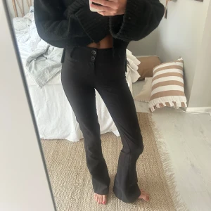 Svarta kostymbyxor - Säljer ett par svarta bootcut kostymbyxor med två knappar framtill. Sitter så snyggt på och är väldigt sköna. Lite noppriga (se bild 4) men ändå väldigt fina