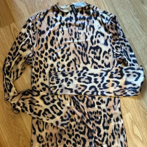 Leopardmönstrad långärmad topp  - Säljer en snygg långärmad topp från H&M divided med leopardmönster i beige och svart. Tight passform och stretchigt material som sitter skönt på kroppen. Perfekt för dig som vill sticka ut med ett djurmönster i garderoben. Helt ny, inte ens testad.