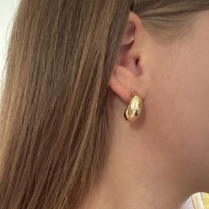 Chunky droppformade örhängen  - Säljer ett par chunky örhängen i droppform med snyggt rundad design. De är i guldig metall och har en clean, modern look som verkligen poppar. Perfekta om du vill ha ett statement men ändå stilrent smycke. Tror de är från Ur&penn!😀Säljer örhängena för de inte kommer till användning!💕💕