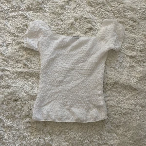 Vit offshoulder topp från Zara - Supersöt vit topp från Zara med offshoulder och korta ärmar. Tunt, vågigt tyg med struktur som ger en cool look. Perfekt till jeans eller kjol när du vill ha något enkelt men ändå speciell🤍