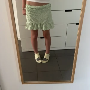 Grön volangkjol från Gina Tricot XS - Supersöt ljusgrön kortkjol från Gina Tricot i storlek XS. Kjolen har små blommiga mönster och en volangkant nertill som ger en extra söt vibe. Perfekt för vår och sommar när du vill ha en fräsch och trendig look.