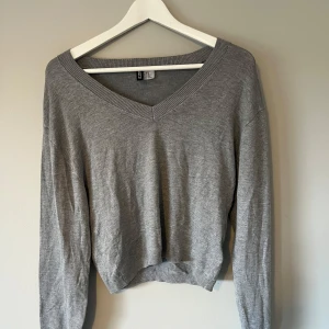 Grå v-ringad tröja H&M Divided XS - Enkel och stilren grå tröja från H&M Divided i storlek XS. V-ringad halsringning och långa ärmar. Mjuk och tunn i bomullsmix, perfekt för lager-på-lager. Endast använd en eller två gånger.