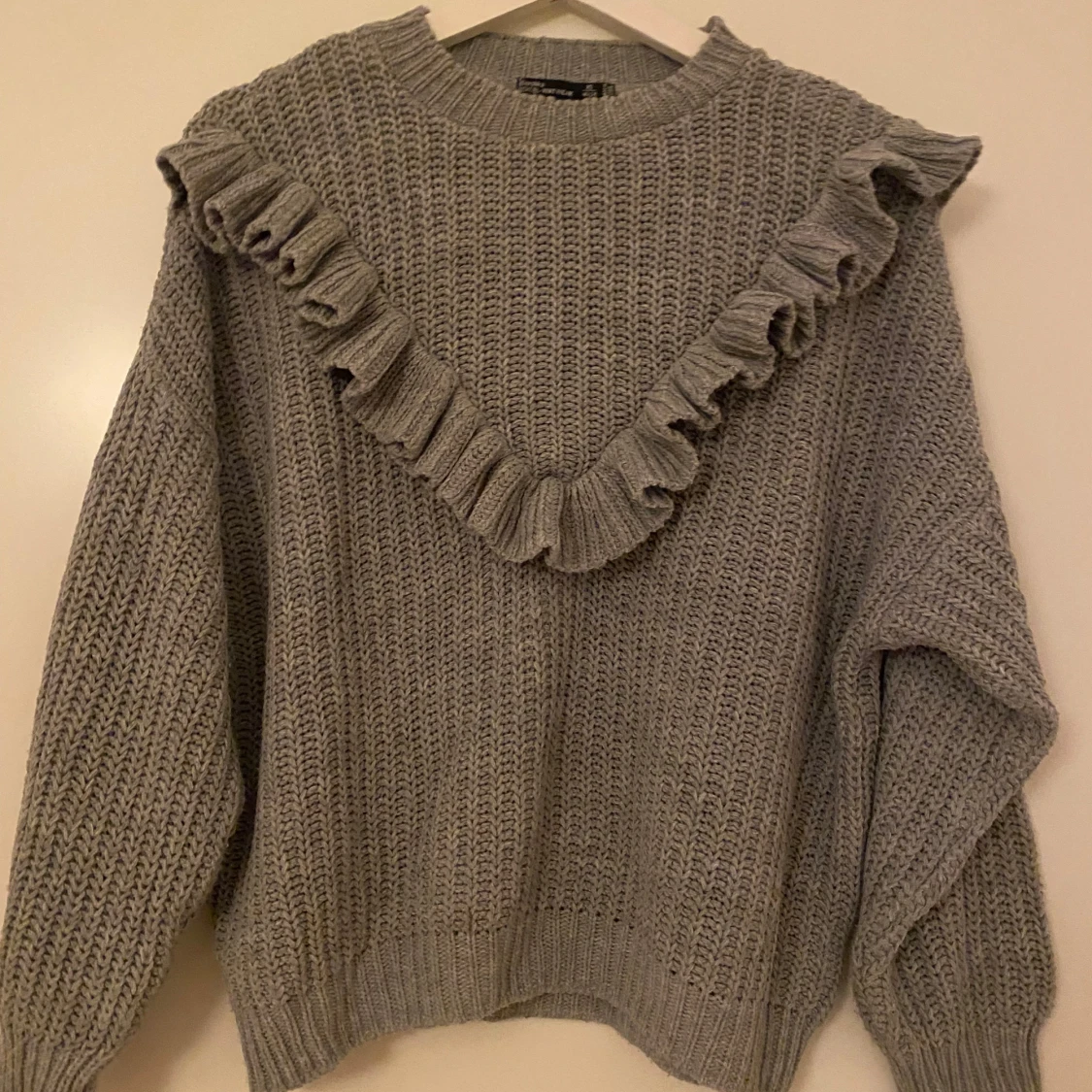 Grå stickad tröja med volang