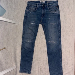 Blå Replay Anbass jeans med slitningar - Säljer ett par blå Replay Anbass jeans med snygga slitningar och andra detaljer - Storlek: 31/30 - Skicket på jeansen är väldigt bra utan några defekter alls - Pris: 800 - Nypris: 1800 - Skriv vid funderingar!