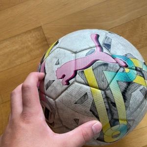 Puma fotboll - Bilderna visar en fotboll från Puma med färgglada detaljer och FIFA Quality-märkning. Produkten är väl använd och har tydliga tecken på slitage. Ingen bok syns på bilderna.