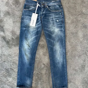 Dondup george, storlek 30 - Snygga blå jeans från Dondup med slitna detaljer och tvättad look. Klassisk femficksmodell med orange sömmar och diskret logga bak. Jeansen har rak passform och är tillverkade i mjukt bomullsjeans. Perfekta för dig som gillar en avslappnad men stilren vibe.