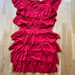Röd volangklänning från Elegance Miss - Superfin röd kortklänning med flera lager volanger och korta ärmar från Elegance Miss. Klänningen är i viskos och har en sorts rynkad detalj på axlarna. Hör av dig om du har frågor! 😊