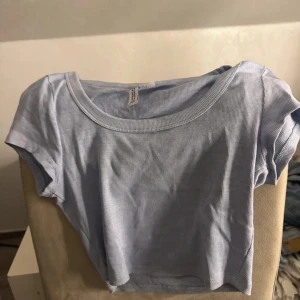 Ljusblå ribbad topp från H&M Divided - Säljer en ljusblå ribbad topp från H&M Divided. Modellen är croppad med korta ärmar och rund halsringning. Perfekt för dig som gillar en enkel men snygg stil. Supermjuk och stretchig i materialet.