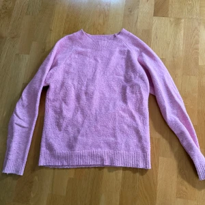 Ljusrosa stickad tröja från Vero Moda - Superfin ljusrosa stickad tröja från Vero Moda. Tröjan har rund halsringning, ribbade muddar och är långärmad. Perfekt för att addera lite färg till din höst- eller vintergarderob. Enkel och mysig modell som är lätt att matcha.