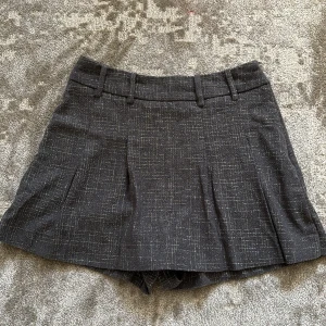 Grå mönstrade shorts från Zara XS - Snygga grå short/kjol från Zara i storlek XS med diskret rutigt mönster och tunna silvertrådar som ger en glittrig touch. Klassisk passform med hällor för bälte och lätt utställda ben.