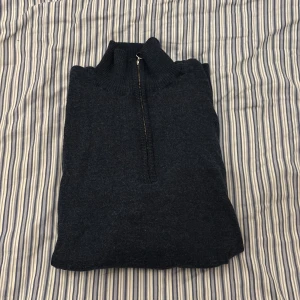 Mörkblå merinoullströja half zip - Säljer en mörkblå stickad tröja från A Day's March i 100% fin merinoull. Tröjan har hög krage och half zip-dragkedja med snygg metallring. Perfekt för lager-på-lager och chill höst- eller vinterstil.