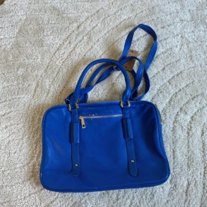 blå väska - man kan använda den som handväska & axelväska. den har slitningar där jag visade och på handtagen. 