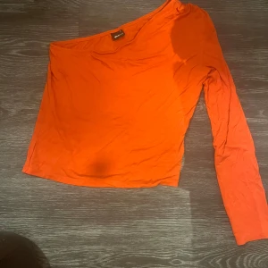 Orange tröja  från Gina Tricot - Snygg orange en armsr topp från Gina Tricot. Ingen fläck på tröjan, min kamera  är trasig 