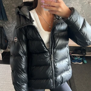 Svart pufferjacka från Colmar - Svart pufferjacka från Colmar med huva i jättebra skick!💖 Den har en cool, lite glansig finish! Nypris 5460 kr. Storleken är 42 skulle säga att den passar som en S!
