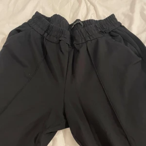 Svarta loose mjukisbyxor med resår - Svarta mjukisbyxor från Divided med bred resår i midjan och raka ben. Byxorna har sidofickor och är gjorda i mjukt bomullsmaterial som är skönt mot huden. Perfekta för chill eller häng med kompisar.