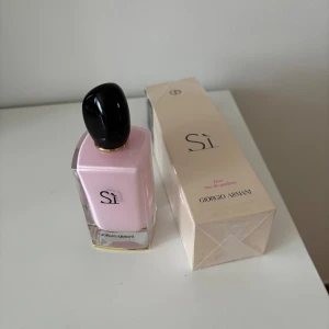 Giorgio Armani Sì Fiori EdP 100ml - Giorgio Armani Sì Fiori Eau de Parfum i en snygg, fyrkantig glasflaska med ljusrosa innehåll och svart lock. Doften är feminin och blommig, perfekt för dig som gillar eleganta och fräscha parfymer. Flaskan rymmer 100 ml och kommer med originalkartong.