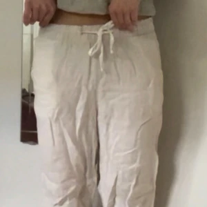 Ljusa Linnebyxor - Snygga linnebyxor med snörning i midjan. De är perfekta för varma dagar. Materialet är linne och byxorna har en enkel, rak design utan mönster eller extra detaljer.