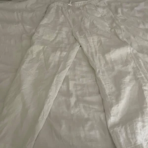 Vita linnebyxor med resårmidja - Säljer ett par fräscha vita linnebyxor med avslappnad passform och elastisk midja. Byxorna har raka ben och är perfekta för varma dagar. Materialet är lätt och luftigt linne, vilket gör dem riktigt sköna att bära. Enkla att matcha med t-shirt eller skjorta.