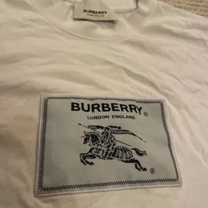 Vit Burberry t-shirt med tryck - Snygg vit t-shirt från Burberry med klassiskt tryck på bröstet i svart och grått. SKRIV INNAN DU KÖPER ⚠️⚠️⚠️⚠️