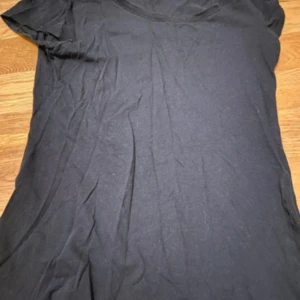 Svart basic t-shirt med v-ringning - En svart t-shirt med v-ringad hals och korta ärmar. Modellen är enkel och klassisk, perfekt för att matcha med jeans eller shorts. Materialet känns mjukt och lätt, troligtvis bomull. Snygg passform som funkar till många olika stilar. Skriv om ni har frågor!