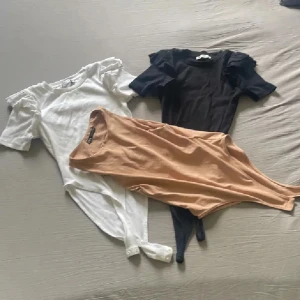 3 Zara body❤️ - Två bodysuits i ribbad bomull, en svart och en vit. Båda har korta ärmar med snygga volangdetaljer på axlarna och rund hals. Perfekt att styla med jeans eller kjol för en clean look. Knäppning nedtill för enkel användning.