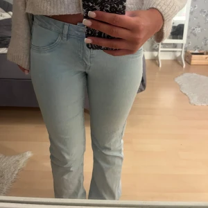 Ljusblå bootcut jeans - Säljer ett par ljusblå jeans med bootcut passform och klassisk femficksdesign. Jeansen har normal midja och är tillverkade i mjukt denimtyg som sitter snyggt och bekvämt. Perfekta för dig som gillar en retro vibe och vill ha ett par jeans som sticker ut.