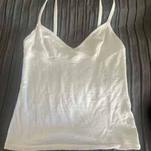 Vit linnetopp från Zara - Fräsch vit linnetopp från Zara med smala axelband och v-ringad hals. Toppen är i mjuk bomull och har en clean, enkel look som är lätt att matcha med jeans eller kjol. Perfekt för varma dagar och chill häng. Snygg passform och stilren design.