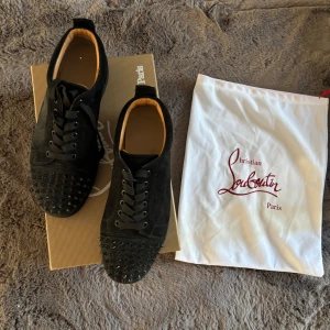 Svarta sneakers från Christian Louboutin - Säljer ett par svarta Christian Louboutin skor storlek 41, väl använda men fortfarande bra skick men därav priset. Låda, dust bag och ersättnings spikes kommer med. Kvitto finns digitalt skickar på meddelande! 